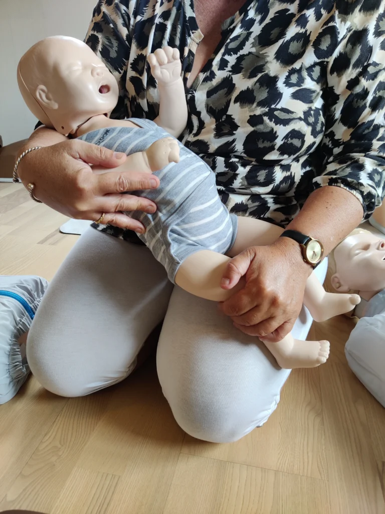 Deltagare håller en spädbarnsdocka i famnen under praktisk barn-HLR-utbildning